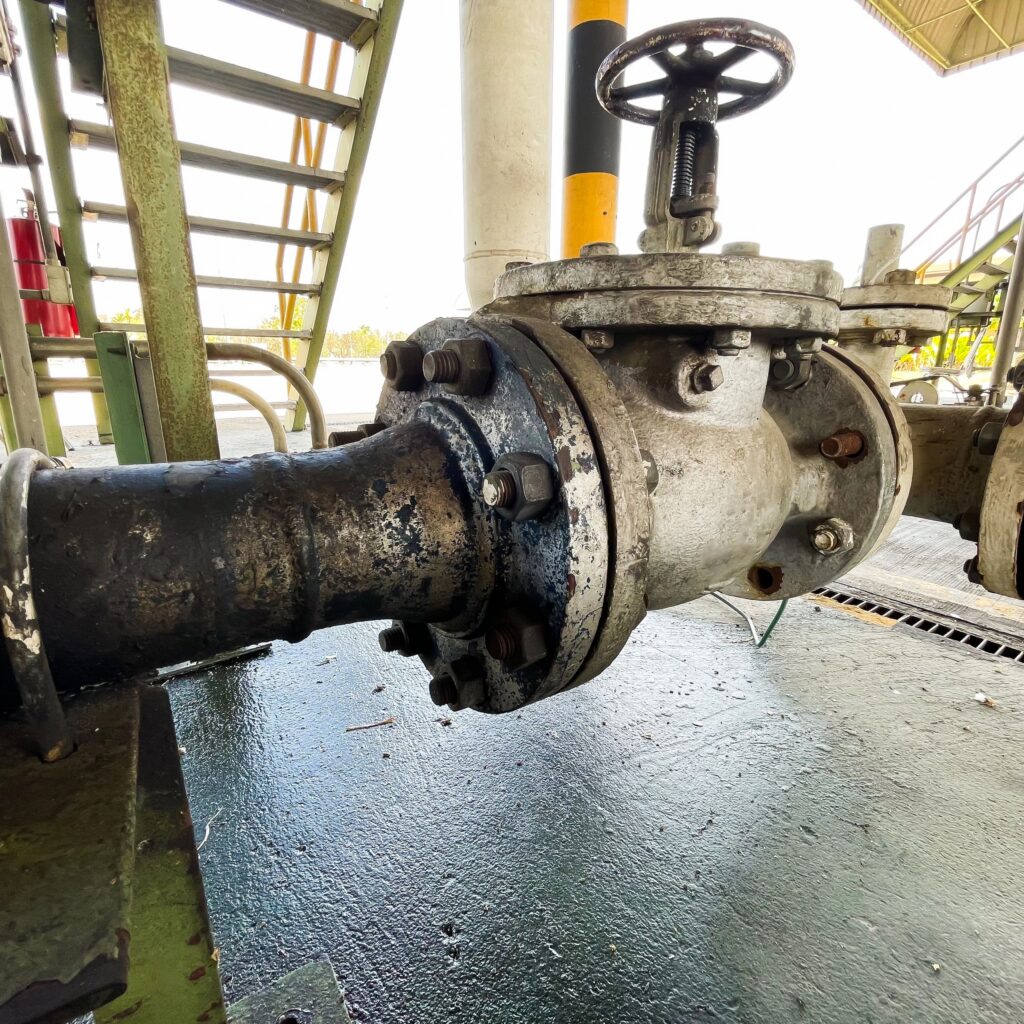 Industrial Pipeline Valve with Oil Leak Stain on Factory Floor in Plant Facility